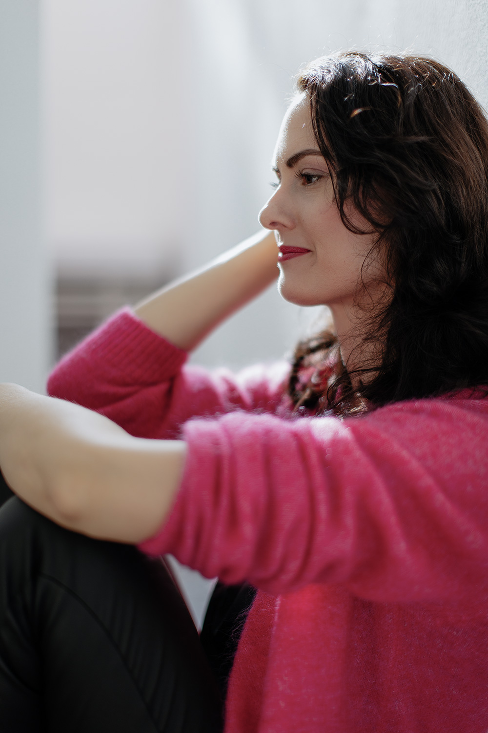 Lisa Pertagnol leicht lächelnd, sitzend mit Strickjacke